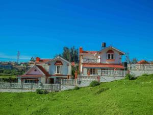 a house sitting on top of a green hill at Pine View Stay Ooty in Ooty