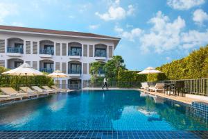 a hotel swimming pool with chairs and umbrellas at Damrei Angkor Hotel in Siem Reap