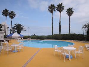 a pool with tables and chairs and palm trees at The Gran Resort Elegante Shirahama in Shirahama