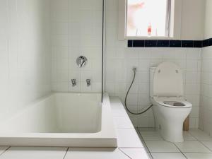y baño blanco con aseo y ducha. en Uptown City Haven - Christchurch Townhouse, en Christchurch