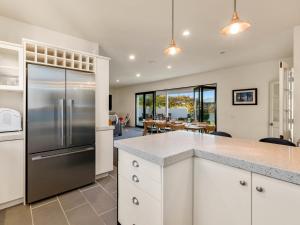 a kitchen with white cabinets and a stainless steel refrigerator at Willowridge Escape - Wanaka Holiday Home in Wanaka