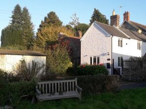 a white house and a bench in the yard at Rose Cottage in Chard