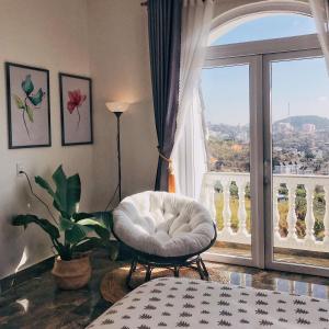 a room with a white chair and a large window at Sally Villa Homestay in Da Lat