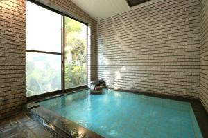 - une grande piscine dans une chambre dotée d'une grande fenêtre dans l'établissement Kintokisan-so, à Hakone