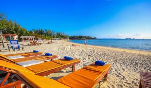 Una playa con mesas y sillas y el océano. en Laemson Resort, en Srithanu