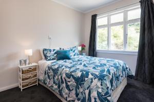 a bedroom with a bed with a blue comforter and a window at Tirohanga Wai - Waikawa Holiday Home in Waikawa