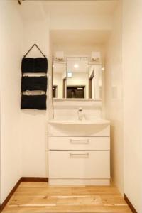 uma casa de banho com um lavatório branco e um espelho. em 大阪之家 心斋桥难波附近4室一厅整套房子5 可接送机场 em Osaka