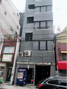 um edifício numa rua da cidade com um carro estacionado em frente em 大阪之家 心斋桥难波附近4室一厅整套房子5 可接送机场 em Osaka