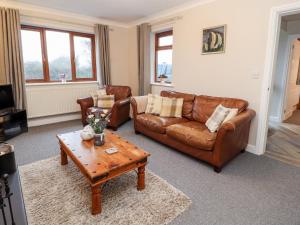 a living room with leather couches and a coffee table at Bryn Seion in Llanddeiniolen
