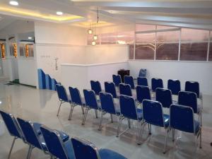 a row of chairs in a room with a white wall at Chrissant Hotel in Yogyakarta
