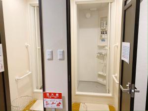 Baño con ducha a ras de suelo junto a una puerta en Nekokura Hostel, en Fukuoka