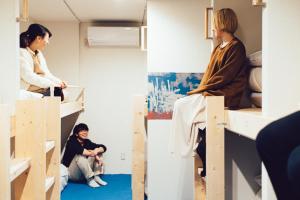 two women sitting on bunk beds in a room at torune in Sapporo