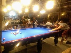 a man is playing pool in a bar at The Seaside Bungalow Hostel and Bar in Hoi An