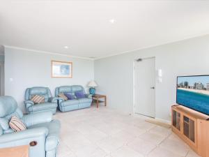 a living room with blue furniture and a flat screen tv at Castillo Del Mar 10 in Tuncurry