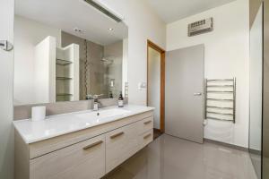 ein Badezimmer mit einem weißen Waschbecken und einem Spiegel in der Unterkunft Infinity Views - Modern Wanaka Holiday Home in Wanaka + 15 Fotos