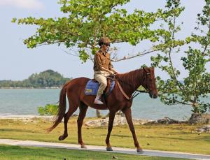 een man rijdt op een paard bij het water bij Indra Maya Pool Villas in Lagoi