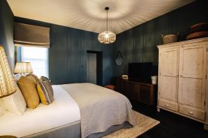 a bedroom with a bed and a cabinet and a chandelier at Blonde Hedgehog in Alderney