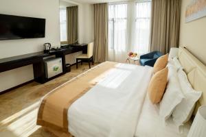 ヤンゴンにあるHotel Sanchaungの大型ベッドとテレビが備わるホテルルームです。