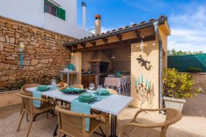 patio ze stołem i krzesłami oraz kamienną ścianą w obiekcie Casa Hermosa w mieście Capdepera