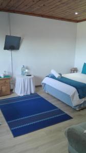 1 dormitorio con cama, mesa y alfombras azules en Guest Lodge on the Edge en Stormsrivier