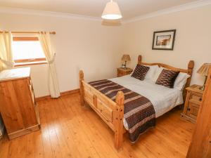 a bedroom with a wooden bed and a window at The Dairy in Llanmorlais