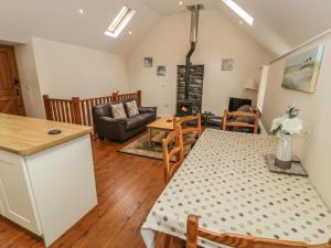 a kitchen and living room with a table and a couch at Hendoll Cottage 2 in Fairbourne