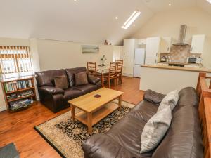 a living room with a leather couch and a table at Hendoll Cottage 2 in Fairbourne