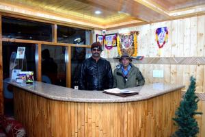 Dois homens num balcão num restaurante. em Hotel Nirmal Chhaya em Manali