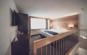 ein Schlafzimmer mit einem Bett und eine Treppe mit einem Fenster in der Unterkunft Hotel Strela by Mountain Hotels in Davos