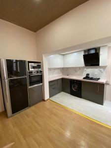 uma cozinha com armários brancos e um frigorífico preto em Cozy Old City Apartment em Baku