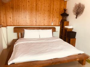 Bett in einem Zimmer mit einer Holzwand in der Unterkunft 睡海邊-小木屋 in Suao