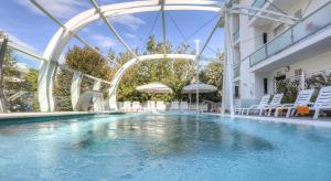 a swimming pool in a building with white chairs and a pool at Hotel Boemia in Riccione