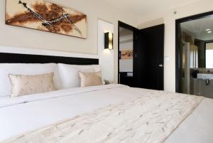 a bedroom with a large white bed with a picture on the wall at ASTON Denpasar Hotel & Convention in Denpasar