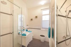 ein weißes Bad mit einem Waschbecken und einer Dusche in der Unterkunft Villa Wiederkehr Einkehr in Ostseebad Sellin