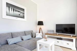 ein Wohnzimmer mit einem grauen Sofa und einem Flachbild-TV in der Unterkunft Villa Wiederkehr Heimkehr in Ostseebad Sellin