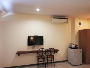 Habitación con 2 sillas y TV en la pared. en Laemsai Resort, en Thalang