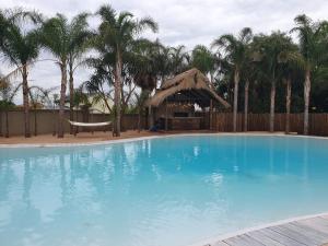 Pretoria的住宿－La-Perna Guesthouse and Venue，一个带凉亭和棕榈树的大型蓝色游泳池