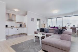 a living room with a couch and a table and a kitchen at Apartamenty Pegaz by Renters in Świnoujście