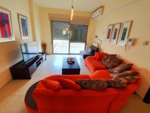 uma sala de estar com um sofá laranja e uma televisão de ecrã plano em Karma Apartment - Next to sandy beach em Chania Town