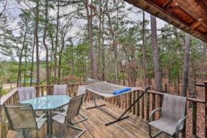 a hammock on a deck with a table and chairs at Authentic Log Cabin with Fire Pit, Pond, and More! in Broken Bow