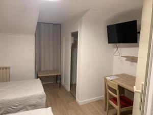 Mały pokój z łóżkiem, biurkiem i telewizorem w obiekcie Le bistrot d eugenie w mieście Eugénie-les-Bains