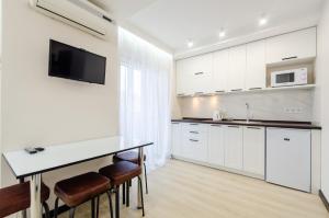 una cucina con armadi bianchi, tavolo e sedie di ARTAL Apartment on Obolonsky avenue 31 a Kiev