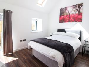 a white bedroom with a large bed and a painting on the wall at Nef-Stedi in Kirktown of Bourtie