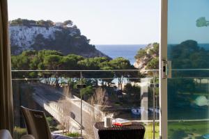 a room with a view of the ocean from a balcony at Minura Cala Galdana & Apartamentos d'Aljandar in Cala Galdana