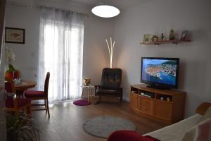 een woonkamer met een televisie, een stoel en een tafel bij Apartments BrunoR in Dubrovnik