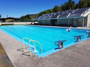 a large swimming pool with blue water in a building at Millers Flat Holiday Park in Millers Flat