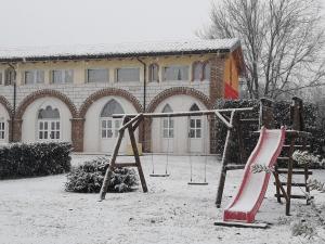 une aire de jeux couverte de neige devant un bâtiment dans l'établissement Agriturismo Villa Stella, à Rivoli Veronese