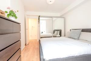 a white bedroom with a bed and a couch at Modern One Bedroom Victoria Apartment in London