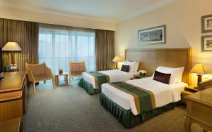 a hotel room with two beds and a desk at City Seasons Hotel Dubai in Dubai