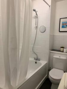 La salle de bains est pourvue d'une baignoire, de toilettes et d'une douche. dans l'établissement Modern One Bedroom Victoria Apartment, à Londres